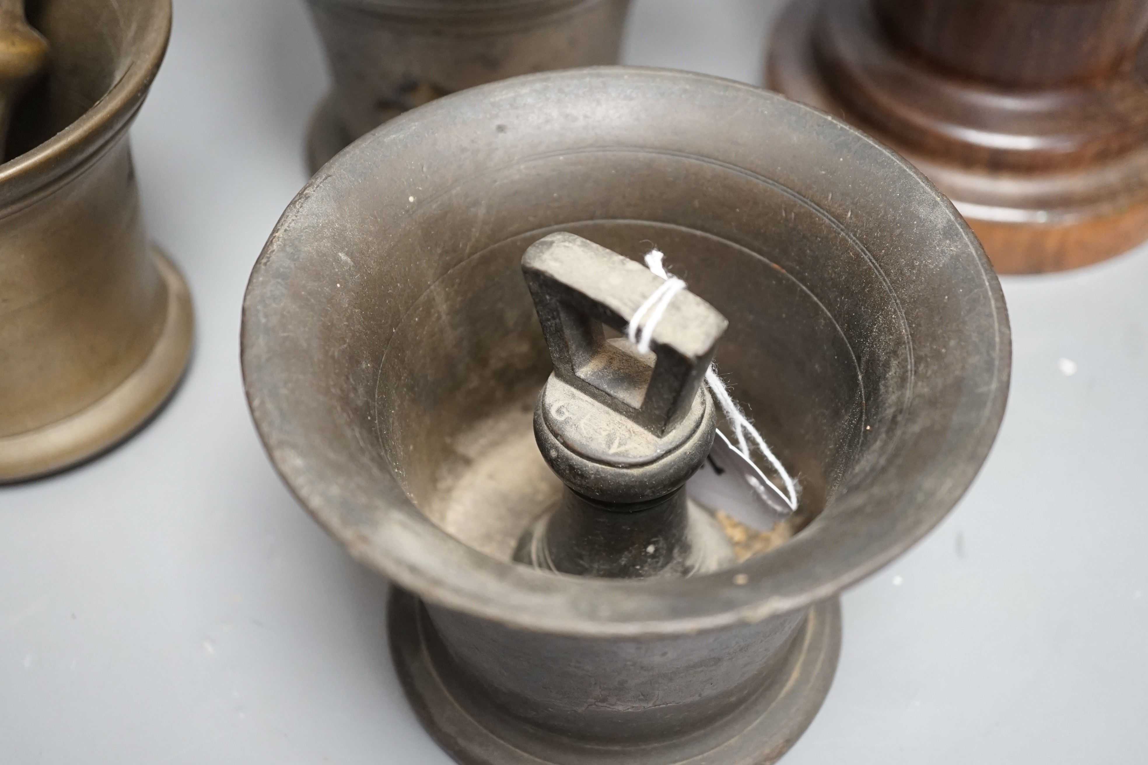 Three bell metal mortars, two pestles, a turned lignum vitae mortar and three postal weights, urn height 20cm